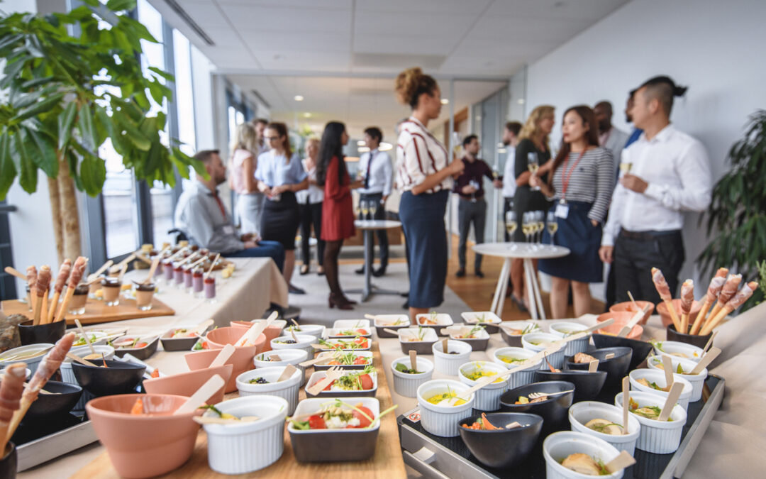 Corporate holiday party - A table filled with food and a group of diverse employees in the background during a company party.